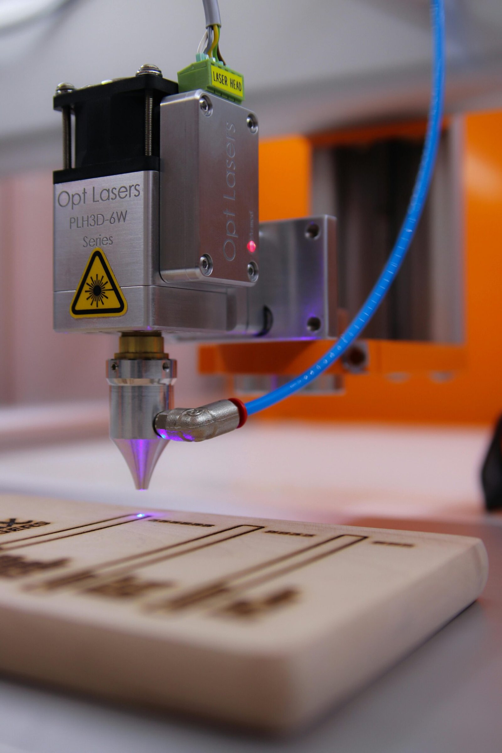 High-tech laser engraving machine working on wooden surface.